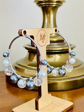 Load image into Gallery viewer, Beaded earrings on a wooden stand with a brass lamp in the background
