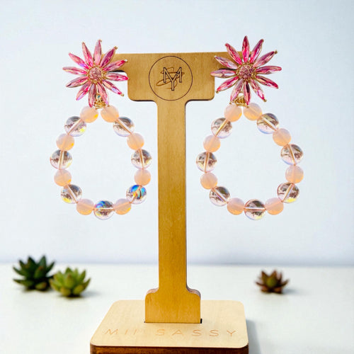 Pink flower earrings on a wooden display stand with 'Millyassy' branding.