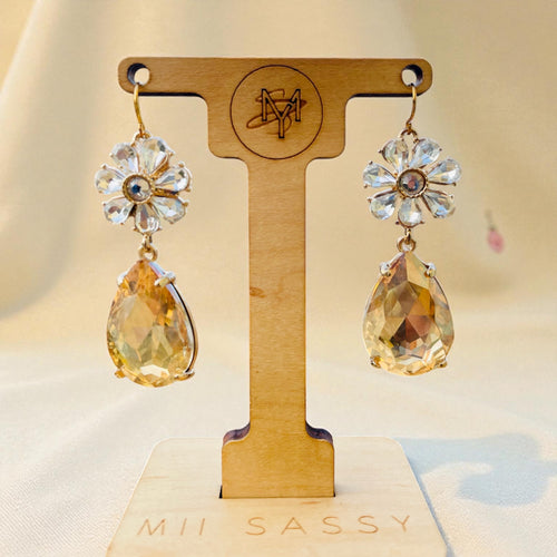 Pair of earrings on a wooden display stand with 'Mii Sassy' branding.