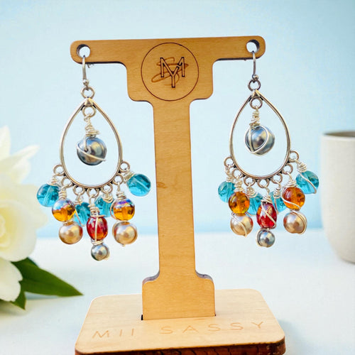 Colorful beaded earrings on a wooden stand with 'Mii Sassy' branding.