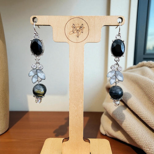 Pair of earrings on a wooden display stand with a blurred background