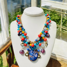 Load image into Gallery viewer, #ClusterBeadedNecklace

#PurpleAndBlueJewelry

#StatementNecklace

#ShortBeadedNecklace

#HandmadeJewelry

#ColorfulNecklace

#BohoAccessories

#ArtisanJewelry

#BoldJewelryStyle

#ChicNecklace
