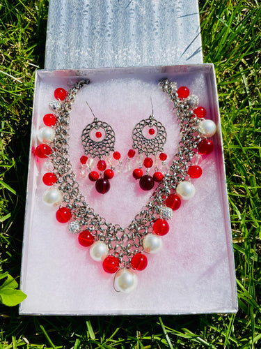 Jewelry set with necklace and earrings on a white box against a grass background

* Red and White Jewelry
* Multi-Colored Beaded Set
* Beaded Necklace and Earrings
* Handmade Jewelry
* Colorful Jewelry
* Boho Jewelry
* Gift for Her
* Holiday Jewelry
* Statement Accessories
* Fashion Jewelry
* Casual Jewelry Set
* Women's Necklace Set
* Red Jewelry
* Matching Jewelry Set
* Handmade Necklace
* Beaded Earrings
* Unique Jewelry
* Festive Jewelry
* Vibrant Jewelry
* Summer Accessories
