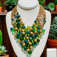 Load image into Gallery viewer, Colorful beaded necklace on a mannequin bust with plants in the background
