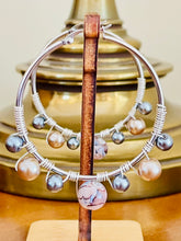 Load image into Gallery viewer, Jewelry stand with silver hoop earrings featuring pearls on a wooden surface.
