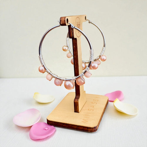 Jewelry stand with pink beaded hoop earrings on a light background