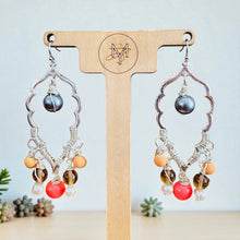 Load image into Gallery viewer, Pair of earrings with colorful beads on a wooden stand with a brand logo. Pair of silver earrings with colorful beads on a wooden stand with blurred natural background
